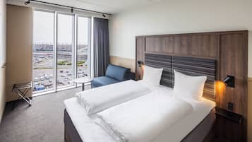 A hotel room with a large bed, a desk, and a view of the city through the window.