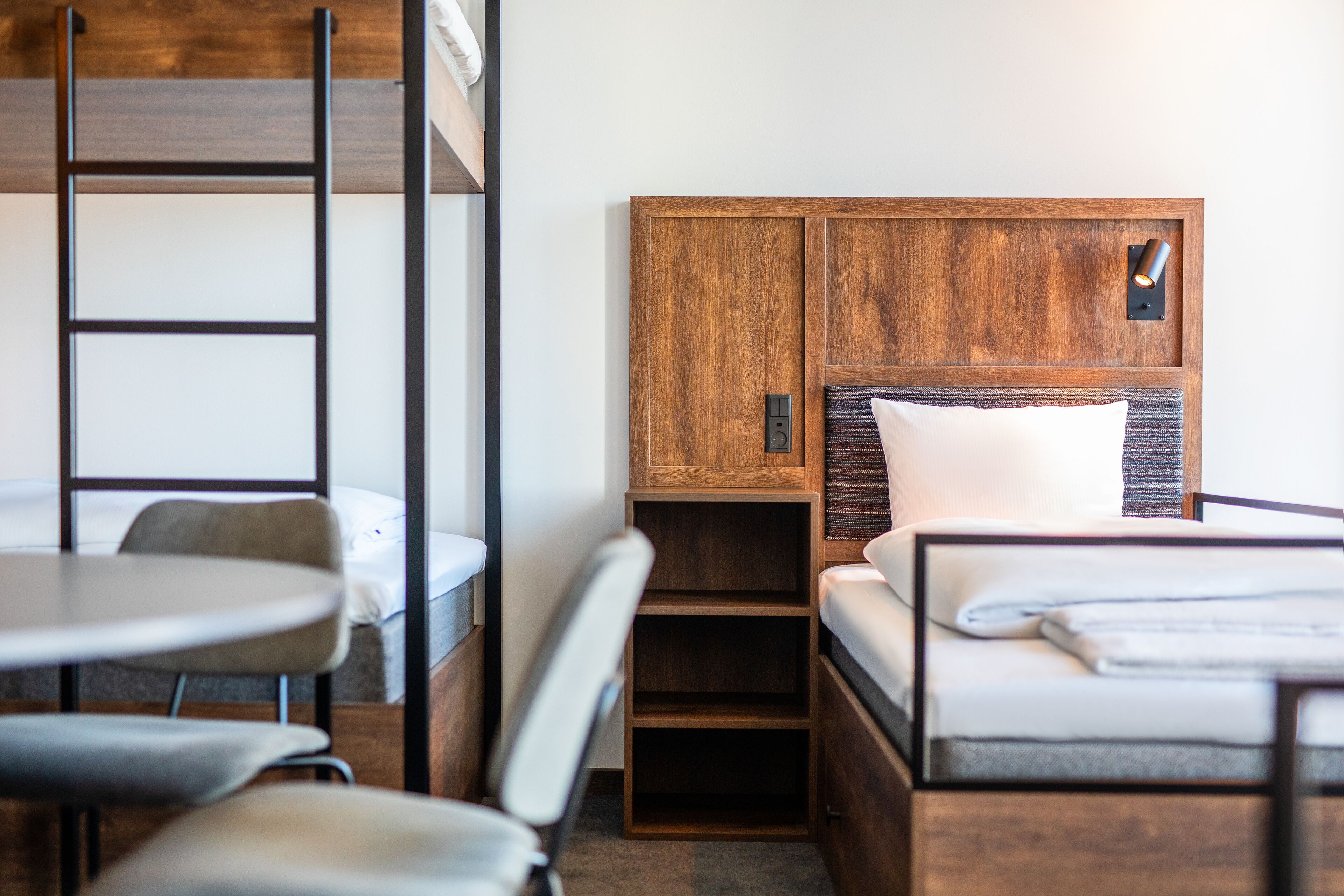 Una habitación de hotel compacta con literas, un escritorio pequeño y una silla.