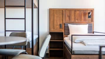 Una habitación de hotel compacta con literas, un escritorio pequeño y una silla.