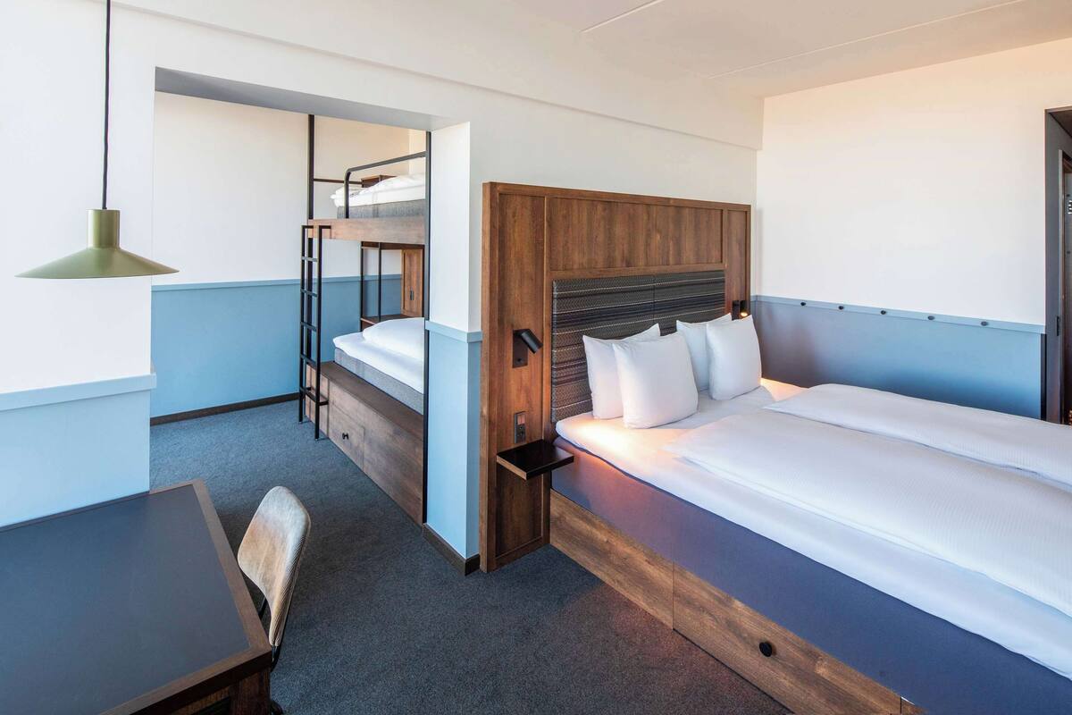 A hotel room with a bunk bed, a desk, and a chair.