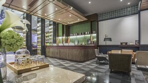 A modern hotel lobby with a check-in counter, seating area, and a decorative plant. - Manxin Hotel Qingdao Zhanqiao (Qingdao)
