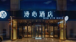 The entrance of Man Xian Hotel with a revolving door and a glass facade. - Manxin Hotel Qingdao Zhanqiao (Qingdao)