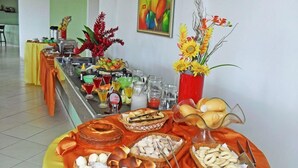 Ein reichhaltiges Buffet mit verschiedenen Speisen und Getränken, darunter Brot, Gebäck und einer Obstauslage.