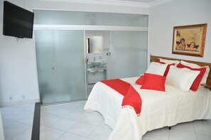 A bedroom with a bed, a television, a sliding door, and a painting on the wall. - Master Hotel (Salinas)