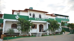 Ein zweistöckiges Hotel mit einer grün-weißen Fassade, einem Schild mit der Aufschrift "MASTER Hotel" und einer Treppe, die zum Eingang führt.