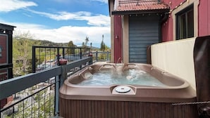 A hot tub on a balcony with a view of a forested area.