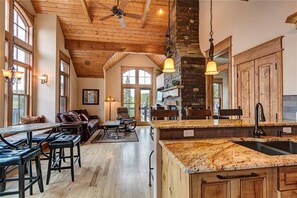Una cocina amplia con chimenea de piedra, techo de madera y ventanas grandes.