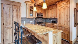 A kitchen with wooden cabinets, a granite countertop, and a hanging light fixture.
