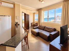 Uma sala de estar moderna com sofá, área de jantar e cozinha equipada com frigorífico.