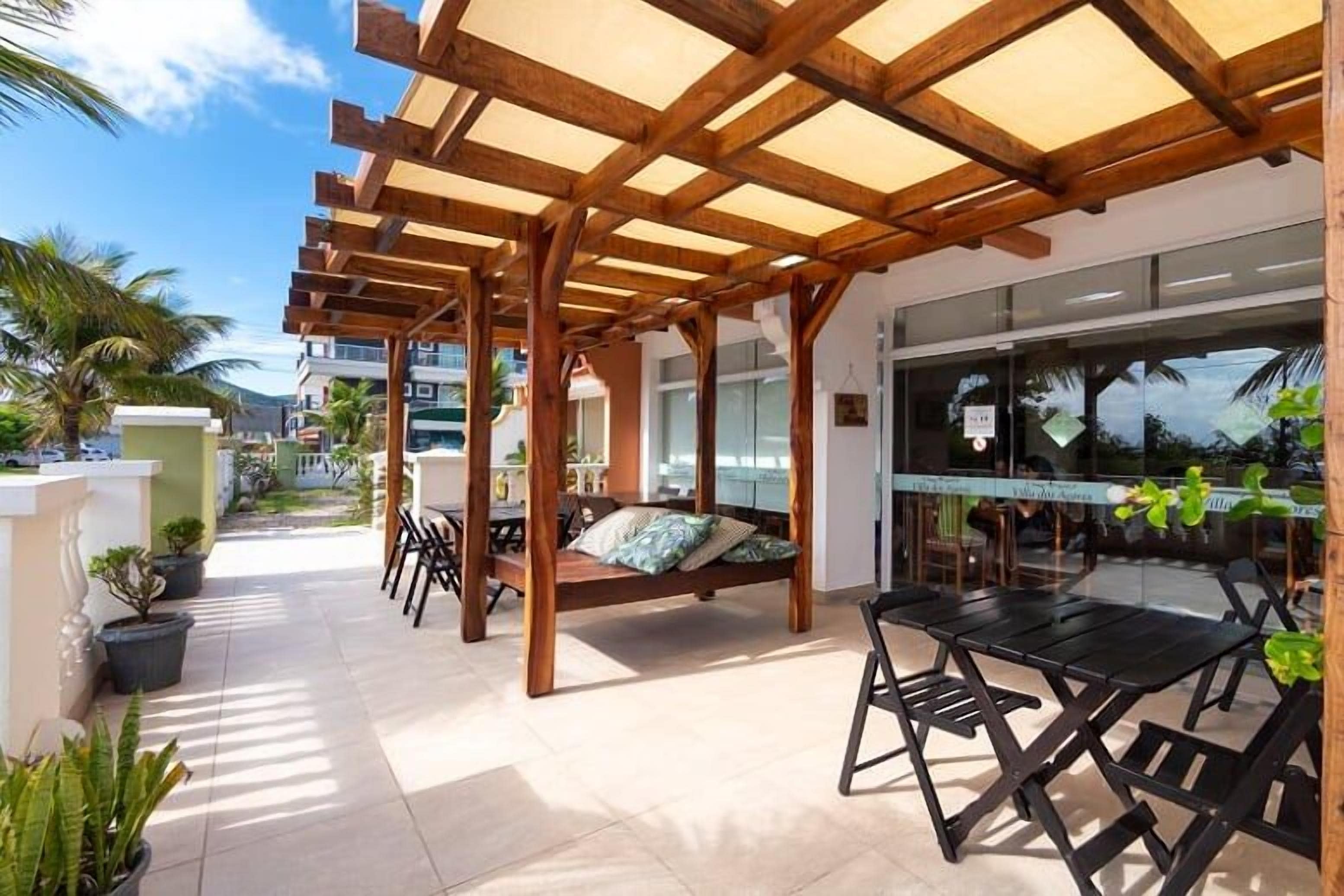 An outdoor patio with wooden pergola, seating, and tables.