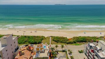 Na praia, areia branca, guarda-sóis