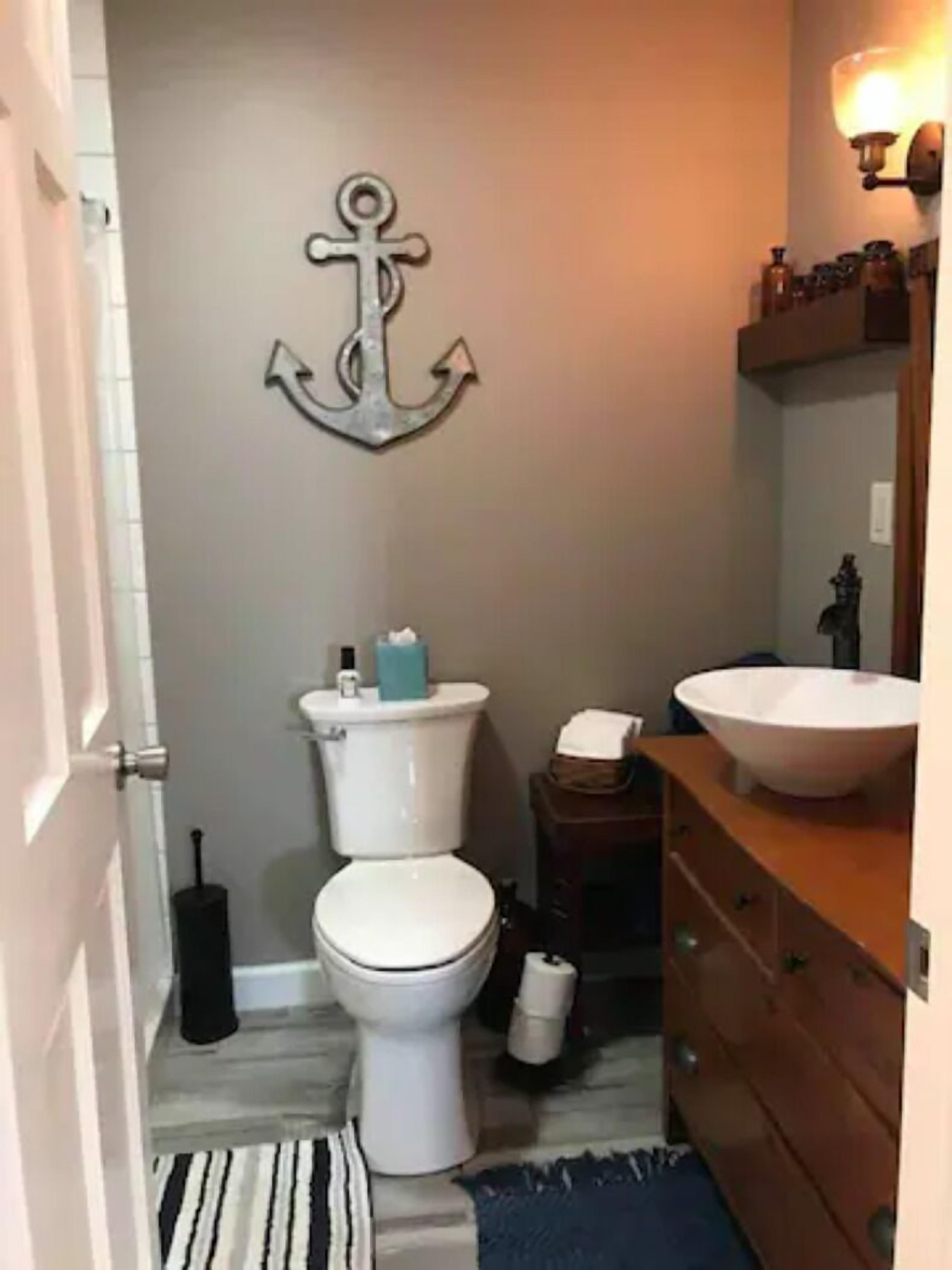 Un bagno piccolo con il water, un lavandino, un tappeto e un punto luce a parete.