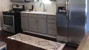 A kitchen with grey cabinets, a stainless steel refrigerator, a microwave, and an oven.