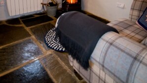 A cozy room with a stone floor, a fireplace, a window, a plaid sofa, and a painting on the wall. - Cozy Irish cottage, located on the Wild Atlantic Way! (Fanore)