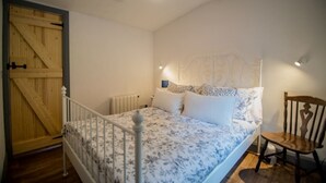 A bedroom with a bed, a chair, a wooden door, and a radiator. - Cozy Irish cottage, located on the Wild Atlantic Way! (Fanore)