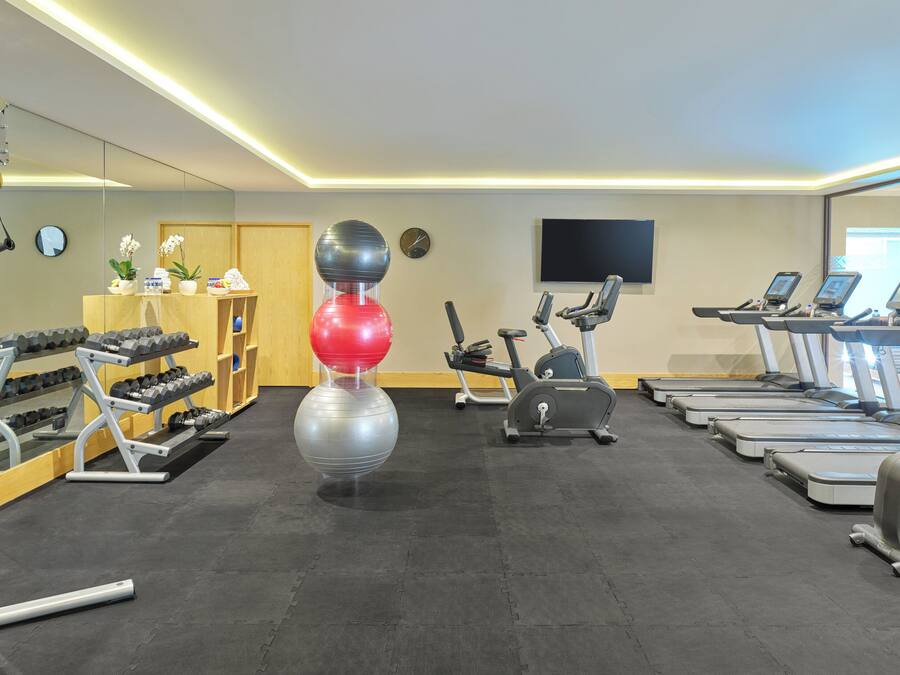 Un gimnasio con cintas de correr, elípticas y pesas sueltas.