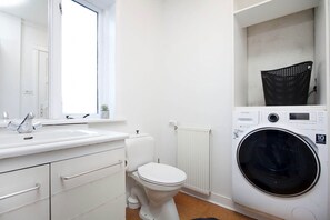 Un baño moderno y funcional, con lavabo, inodoro y lavadora blancos.
