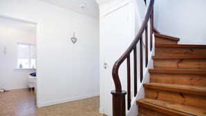 Una escalera de madera con peldaños de madera y una barandilla de madera oscura que lleva a una puerta blanca.