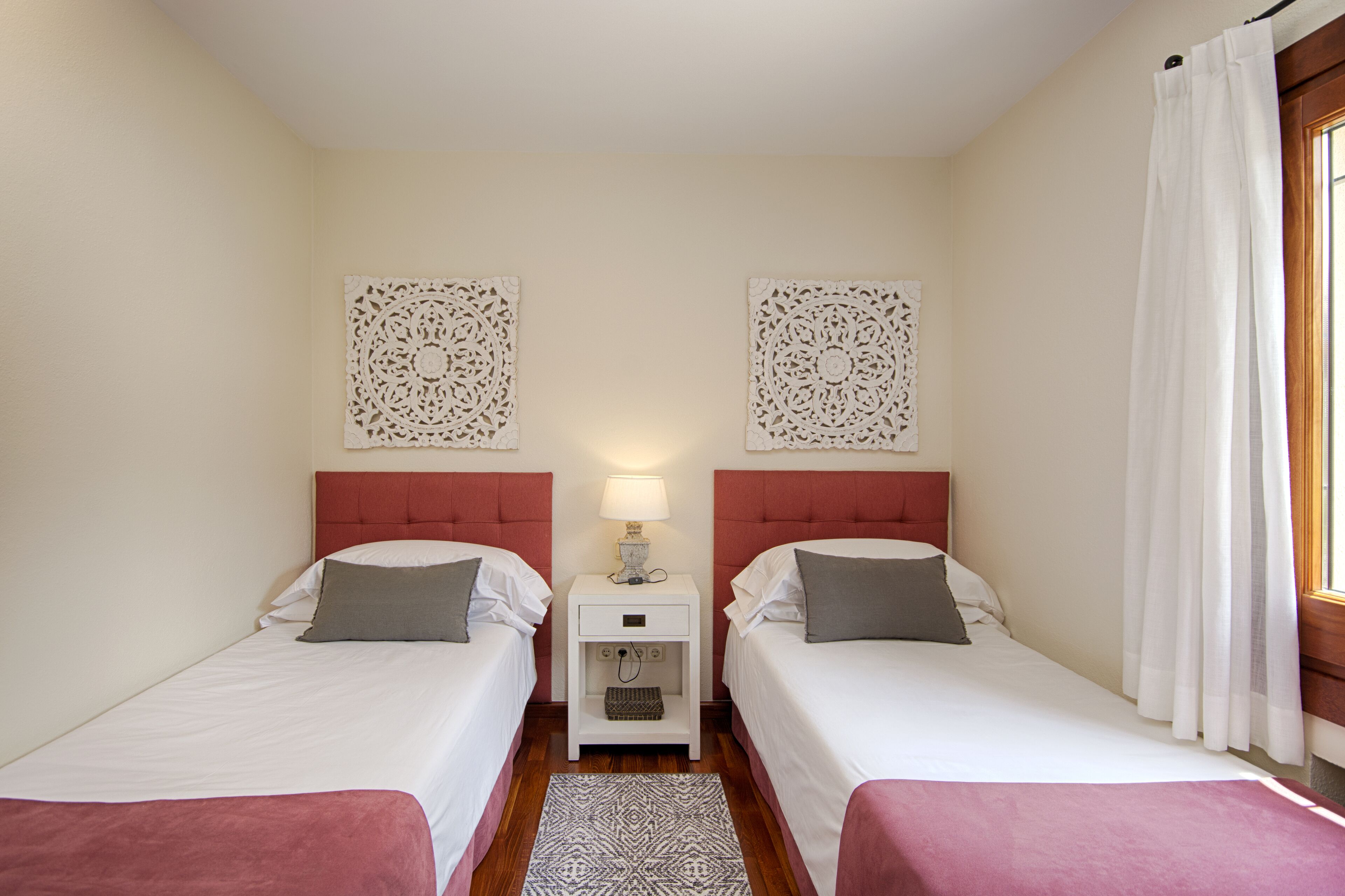 Habitación doble con dos camas, una mesita de noche, una lámpara y decoración en la pared.
