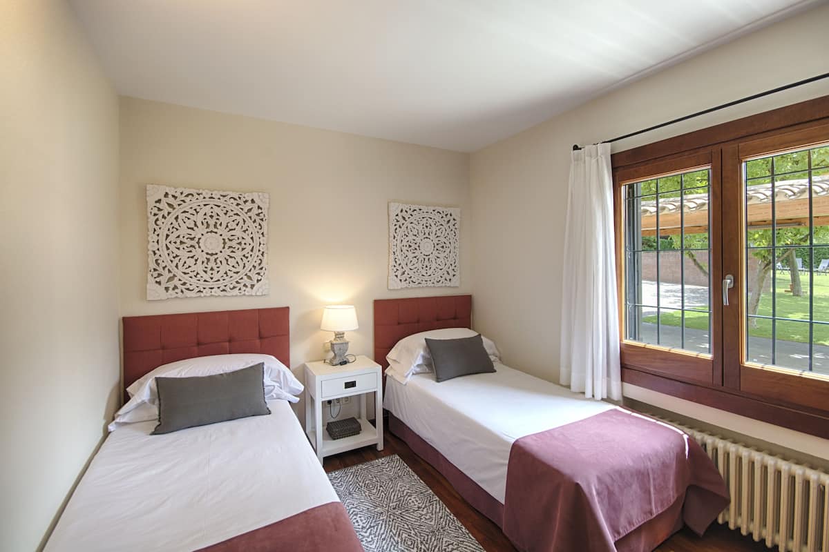 Habitación de hotel con dos camas, ventana con vistas al exterior y decoración en la pared.