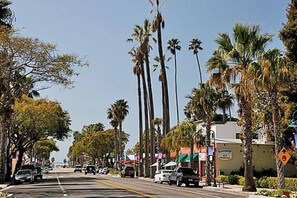 A street lined with palm trees and buildings, including a visible sign for 'Kensington'. - Apt 4: Beautiful unit close to the Sand (Carpinteria)