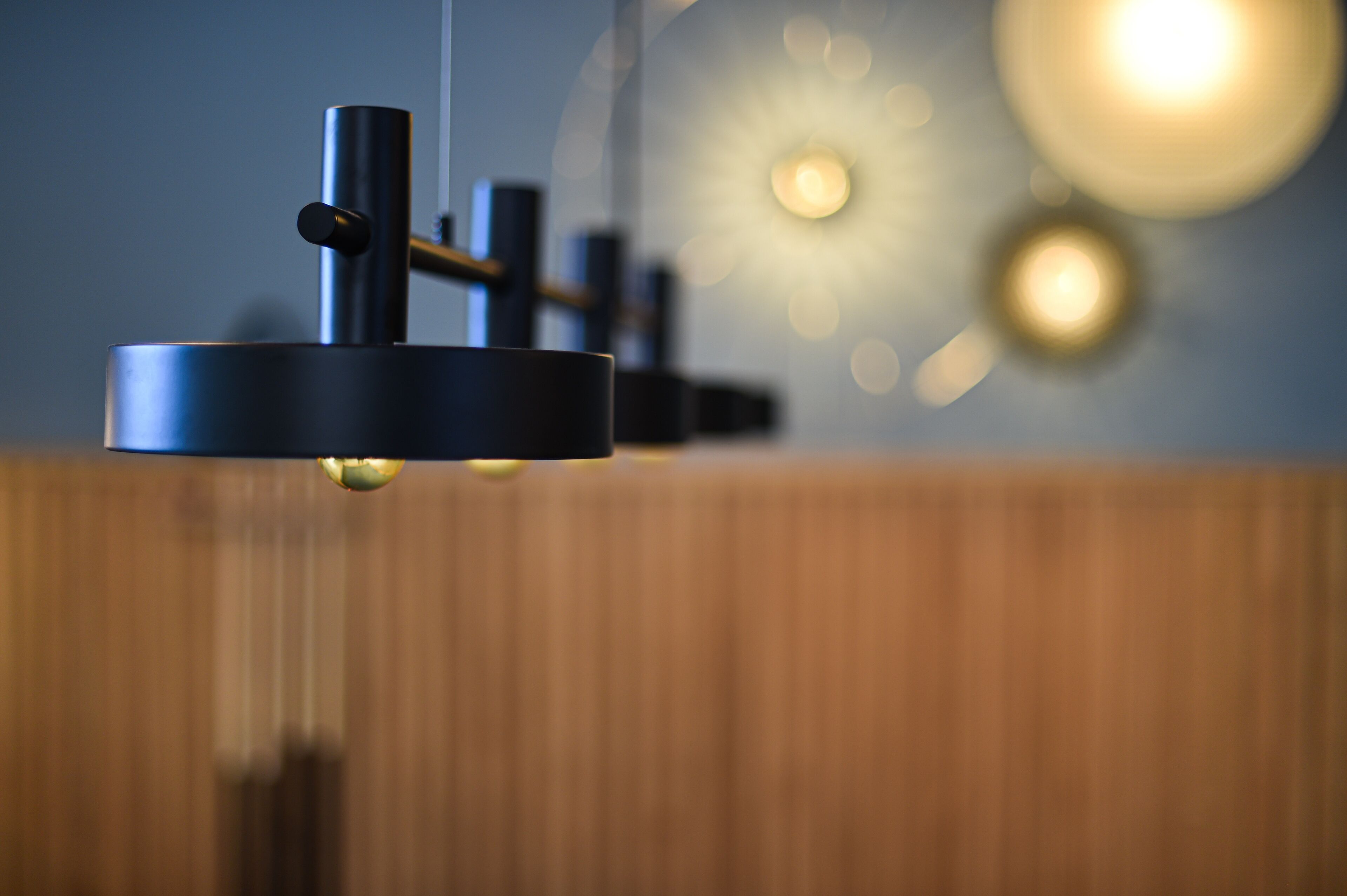 A modern light fixture with a cylindrical base and a hanging element, set against a blurred background with circular light patterns.