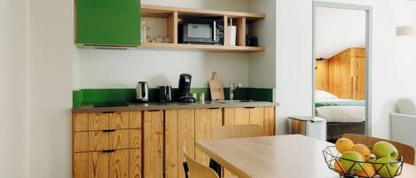 Una cocina compacta con armarios de madera, un microondas y una cafetera.