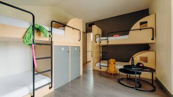 Habitación con literas, un escritorio, una silla, una mesita y una mochila.