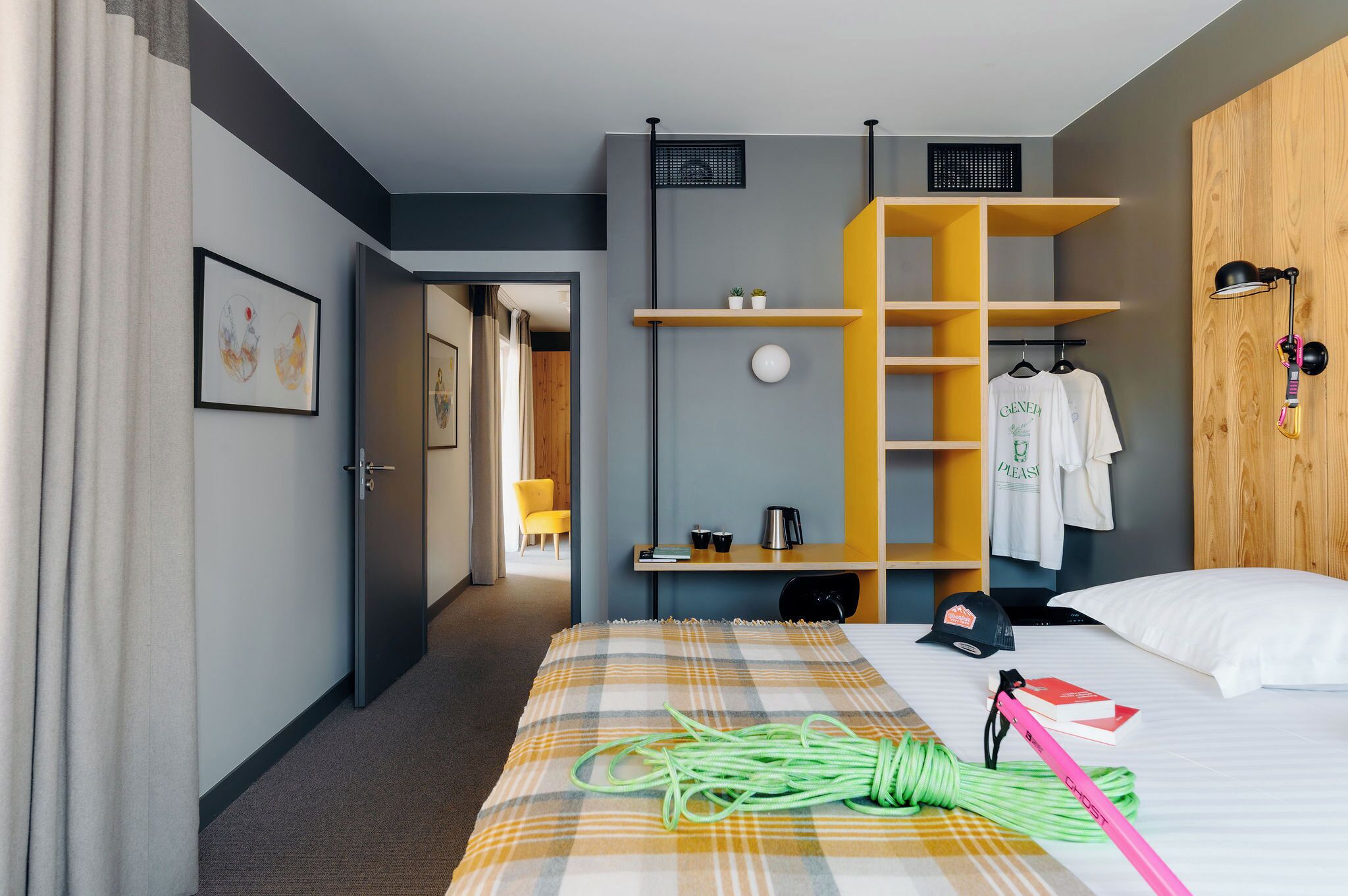 A hotel room with a bed, a desk, a chair, a wardrobe, and a door leading to another room.