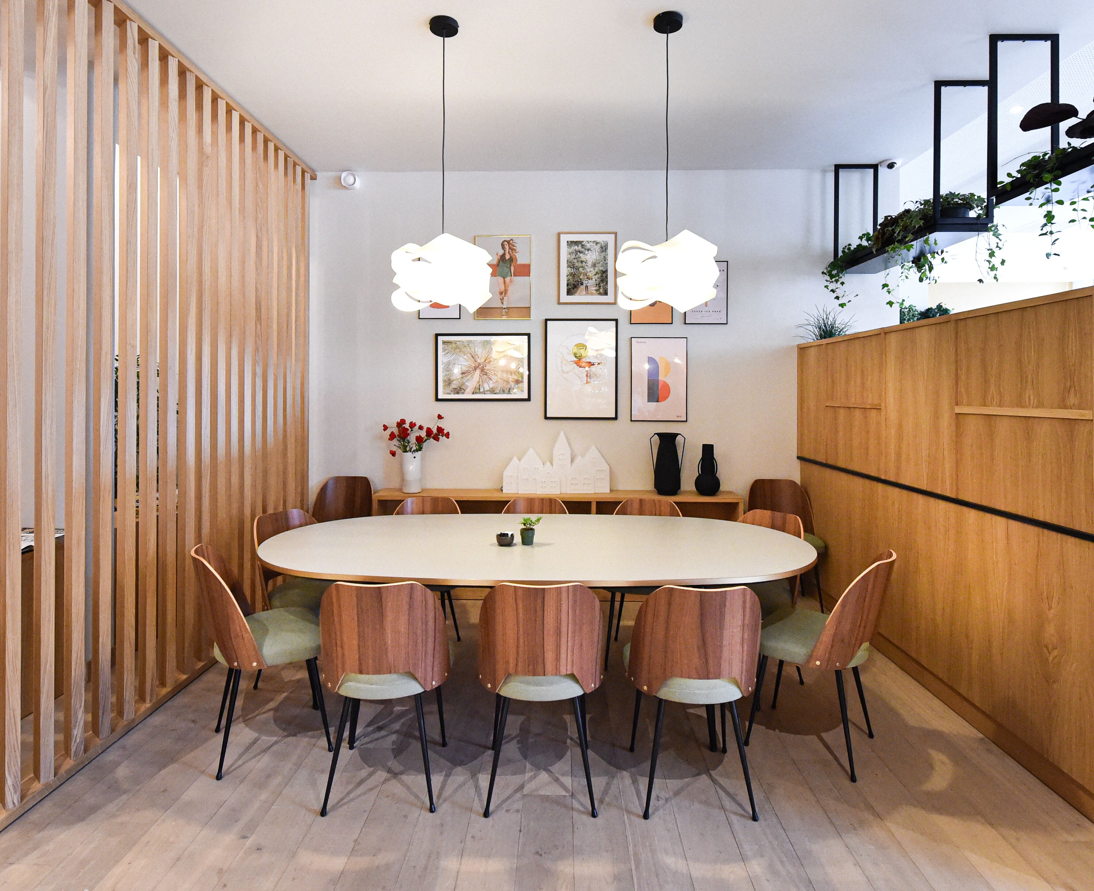 A dining area with a round table, wooden chairs, and hanging pendant lights.