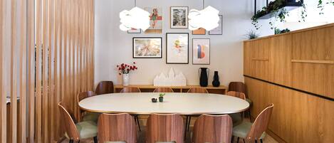 A dining area with a round table, wooden chairs, and hanging pendant lights.