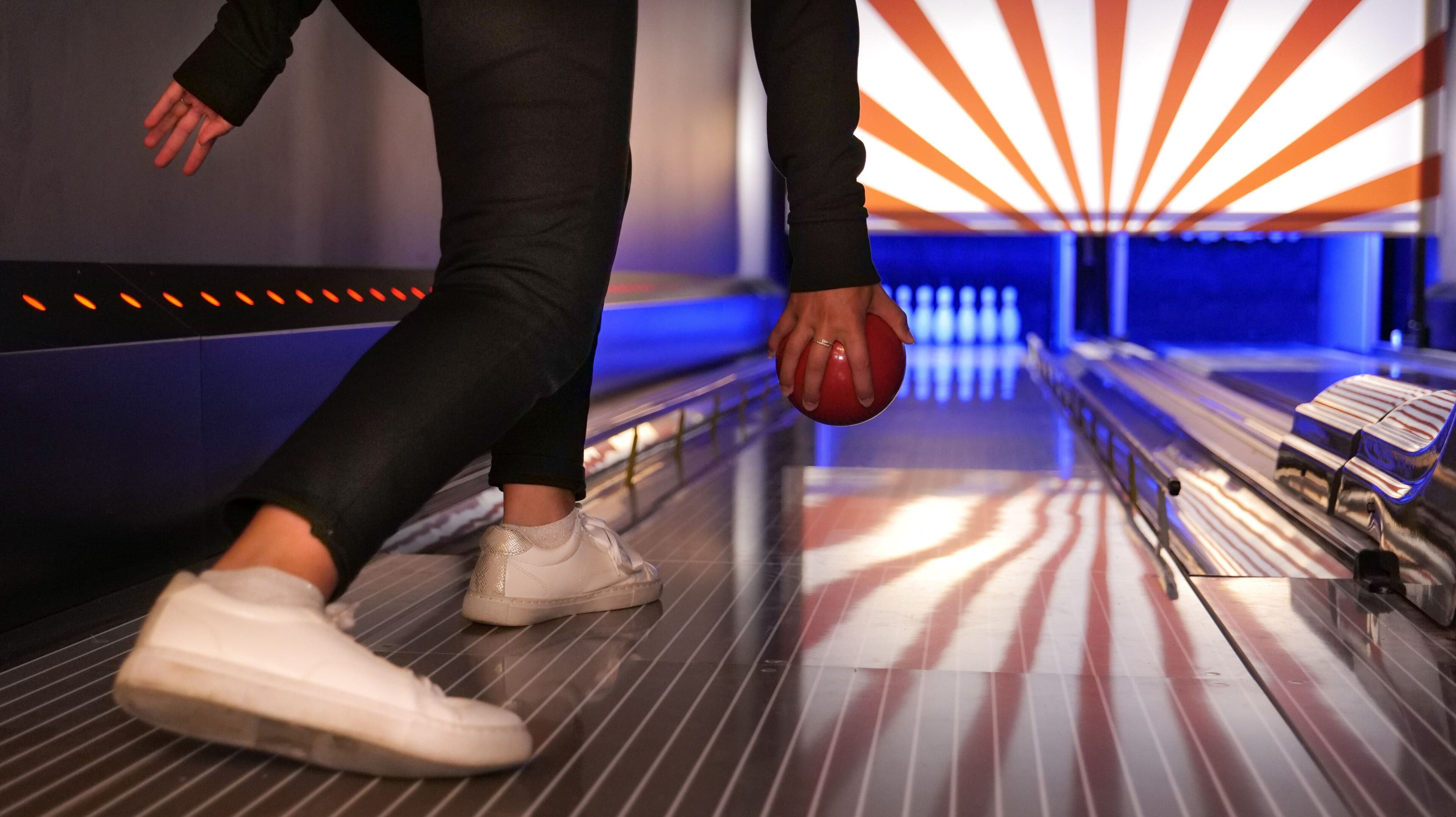 Pista de boliche com alvéolos, uma bola de boliche e uma pessoa em movimento.