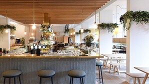 Zona de bar moderna con techo de madera, taburetes y una variedad de botellas y vasos sobre la barra.