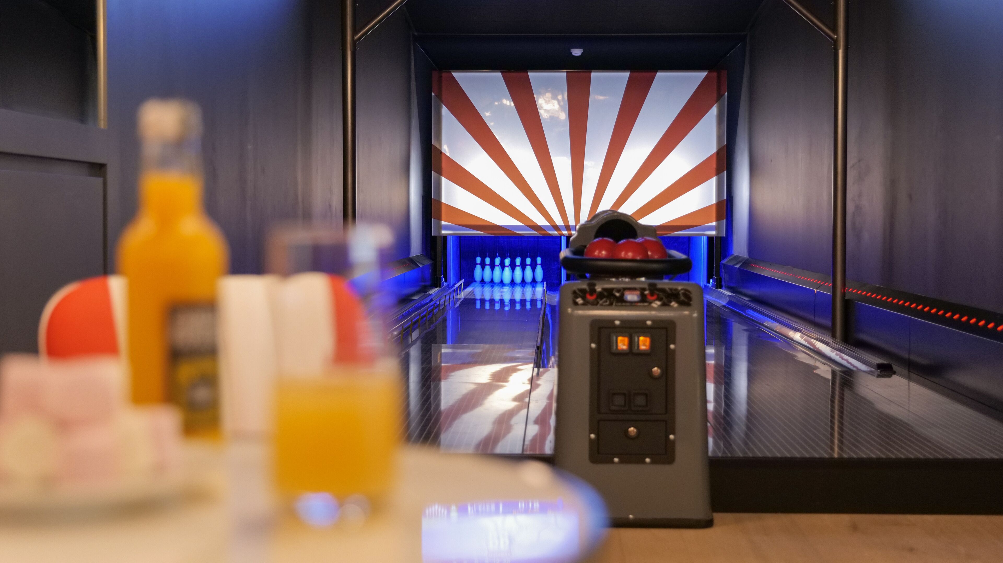 A bowling alley with a modern design, including a bowling ball return system and a neon-lit bowling lane.