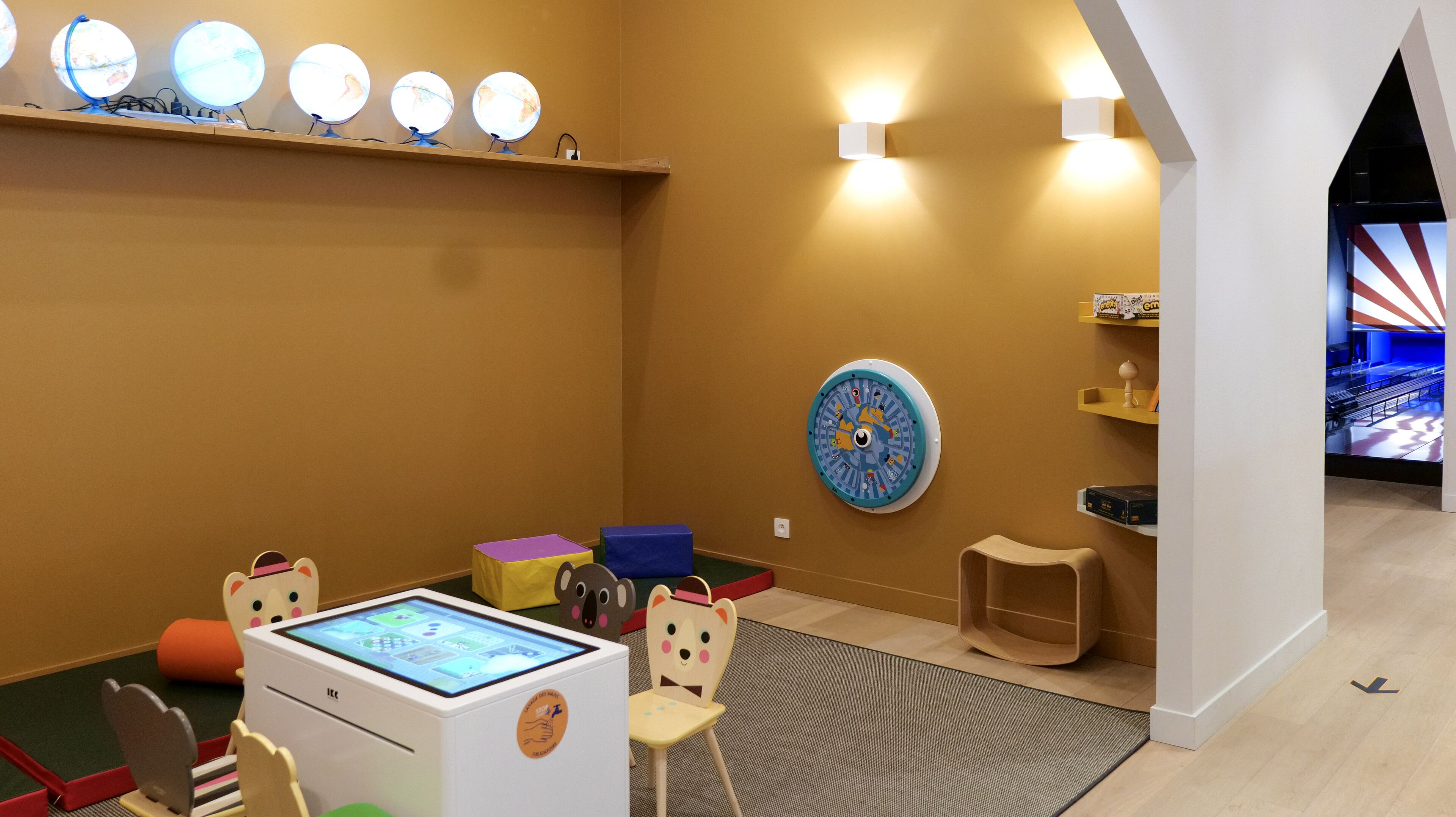 Un área de juegos infantiles con una tableta digital, un reloj y un taburete pequeño.