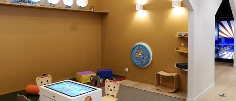 Un área de juegos infantiles con una tableta digital, un reloj y un taburete pequeño.