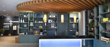 A reception area with a modern design, featuring a wooden ceiling, a reception desk, and shelves with various items.