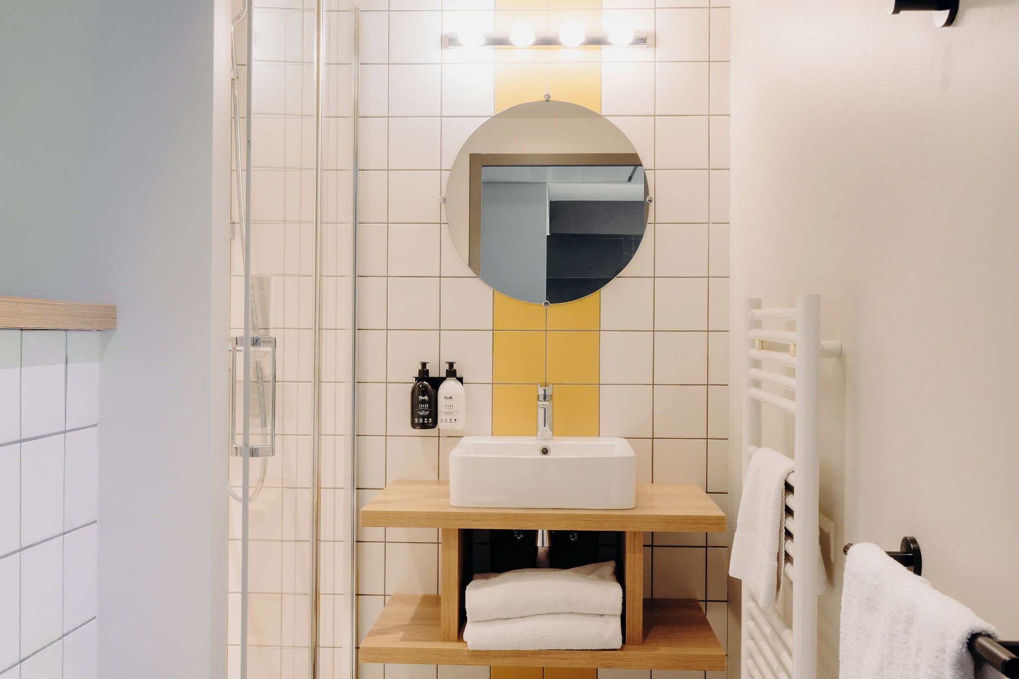 A bathroom with a white sink, mirror, and towel rack.