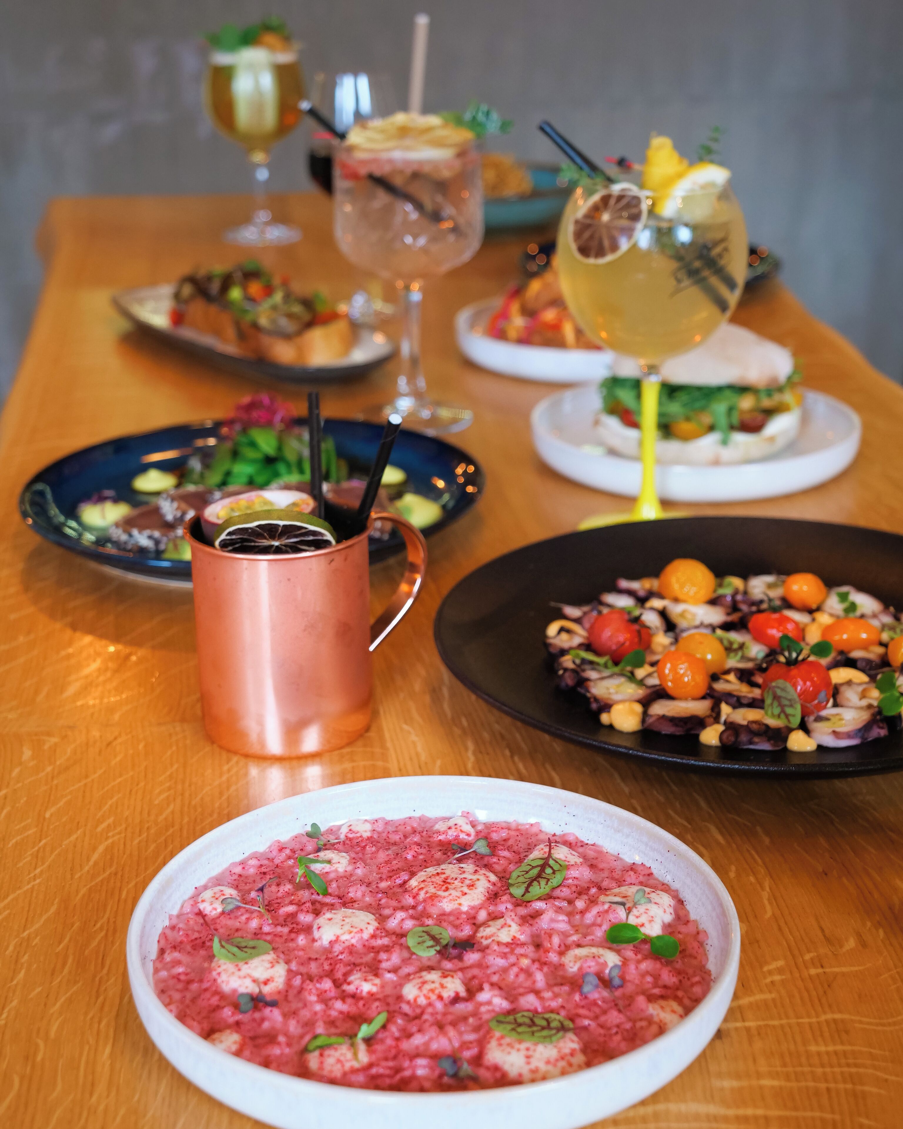 A table with various dishes, drinks, and a copper mug.