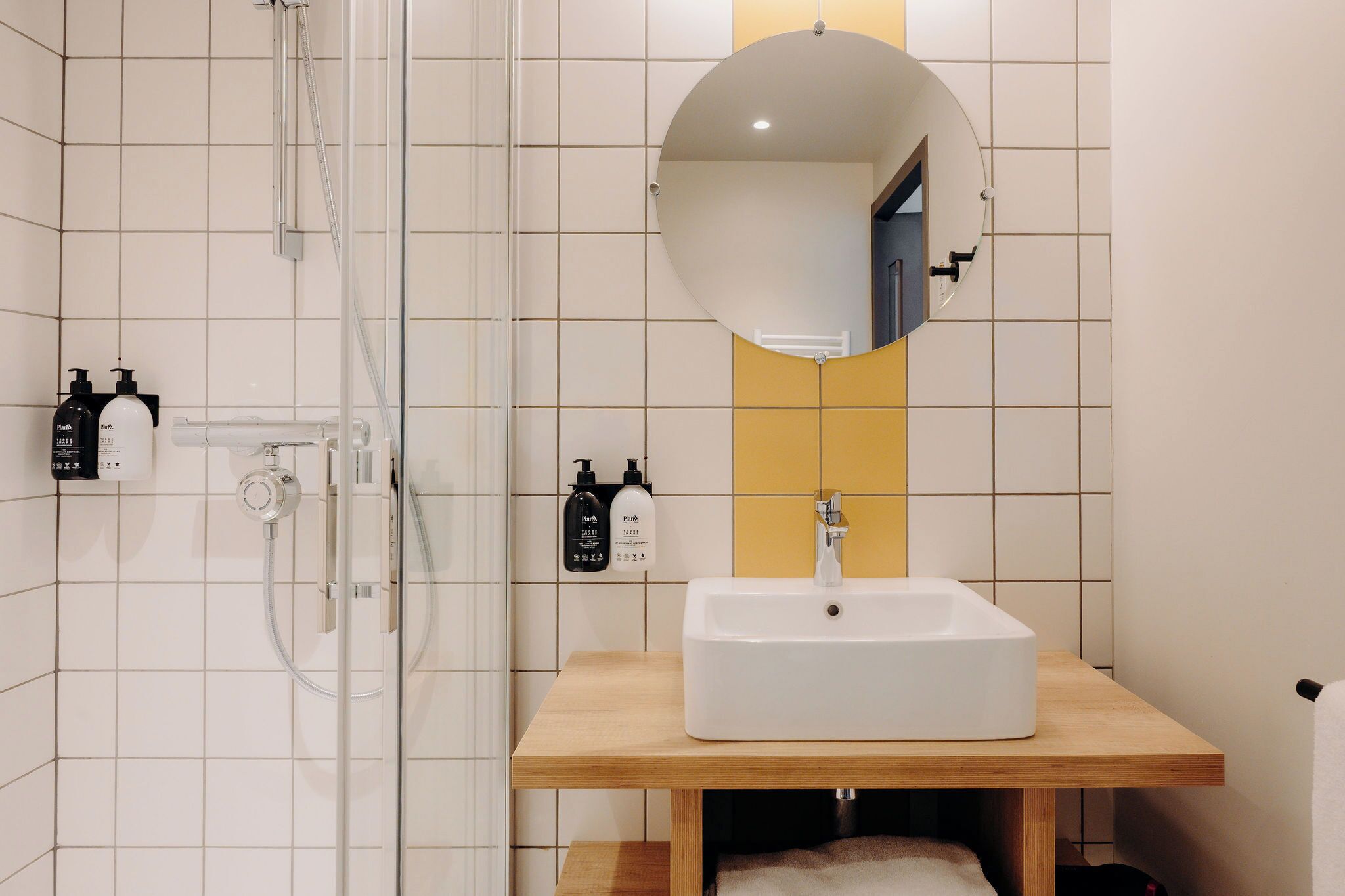 A modern bathroom with a shower, a sink, and a mirror.