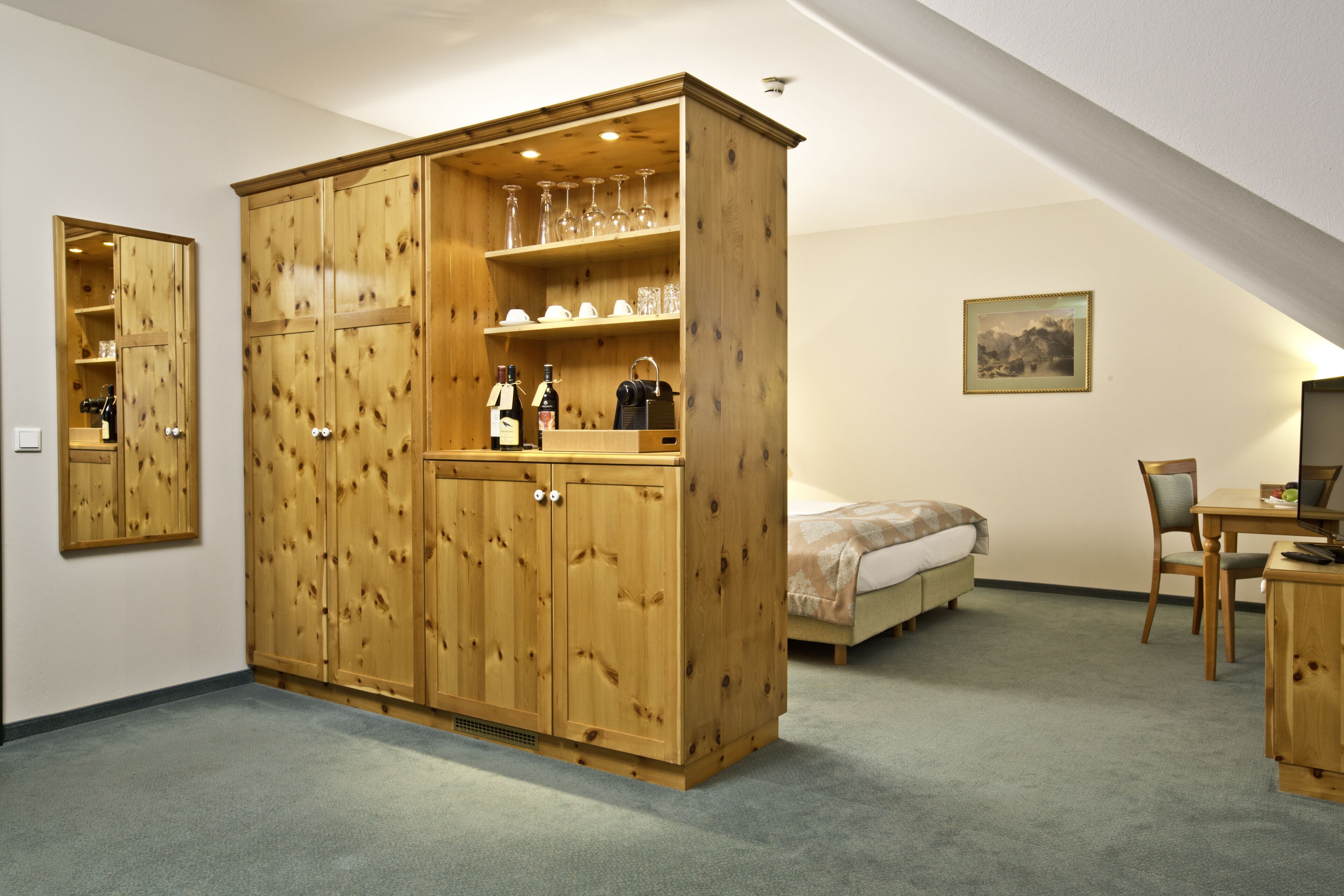 Un dormitorio con un amplio armario de madera, una cama, un escritorio y una silla.