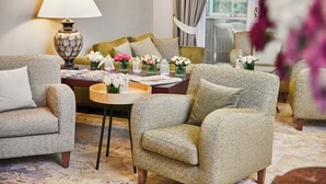 Een woonkamer met gestreept banken, een tafel met een lamp en vazen met bloemen.