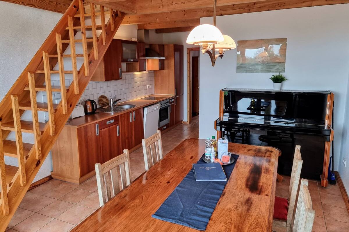A kitchen with wooden cabinets, a dining table, and a piano.