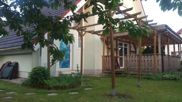 Una casa con pérgola de madera, puerta corrediza y patio trasero cercado.