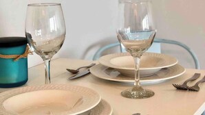 A dining table set with plates, cutlery, and two wine glasses.