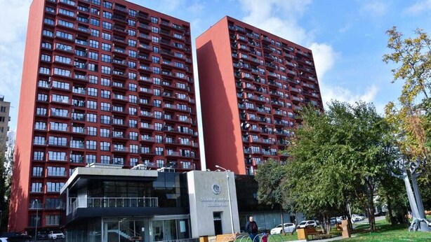 Een hoog gebouw met meerdere verdiepingen, grote ramen en een opvallend entreegebied.