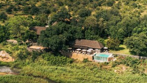 Vue aérienne d’un chalet isolé doté d’une piscine, entouré d’une forêt dense.