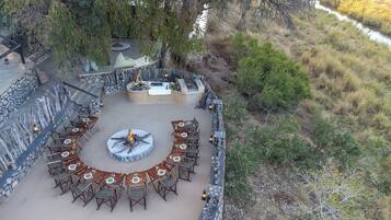 Un patio al aire libre con un conjunto de asientos circulares, muros de piedra y una chimenea.