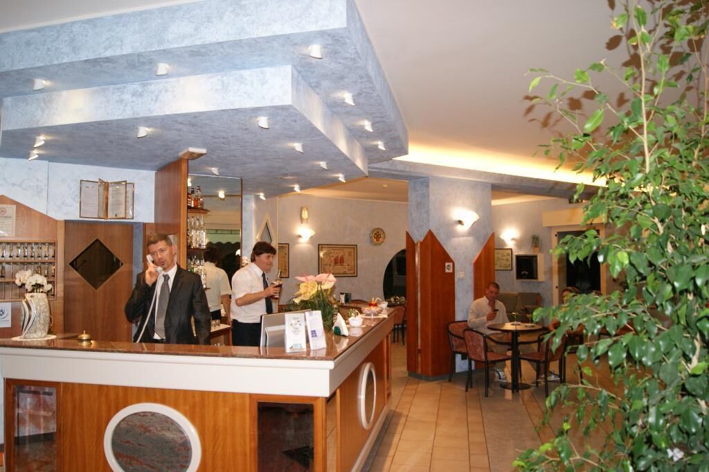 A hotel lobby with a reception desk, seating area, and a bar.