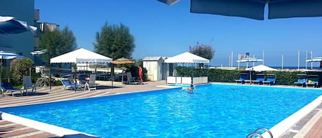 Una piscina al aire libre de temporada, sombrillas